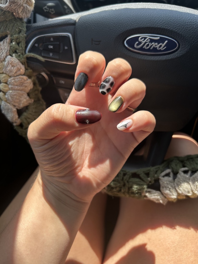A hand with each nail a different color: olive, burgundy, white and gold