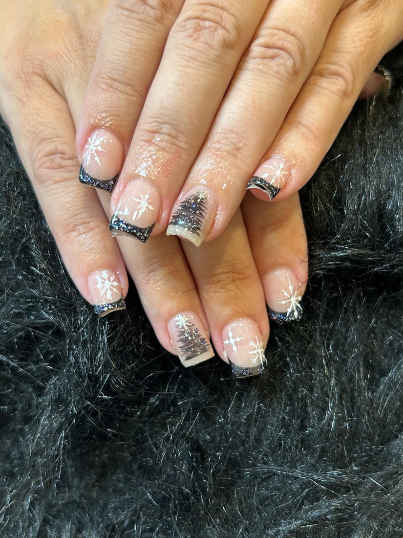Two hands with black and silver French-tip nails decorated with glitter, snowflakes and small crosses