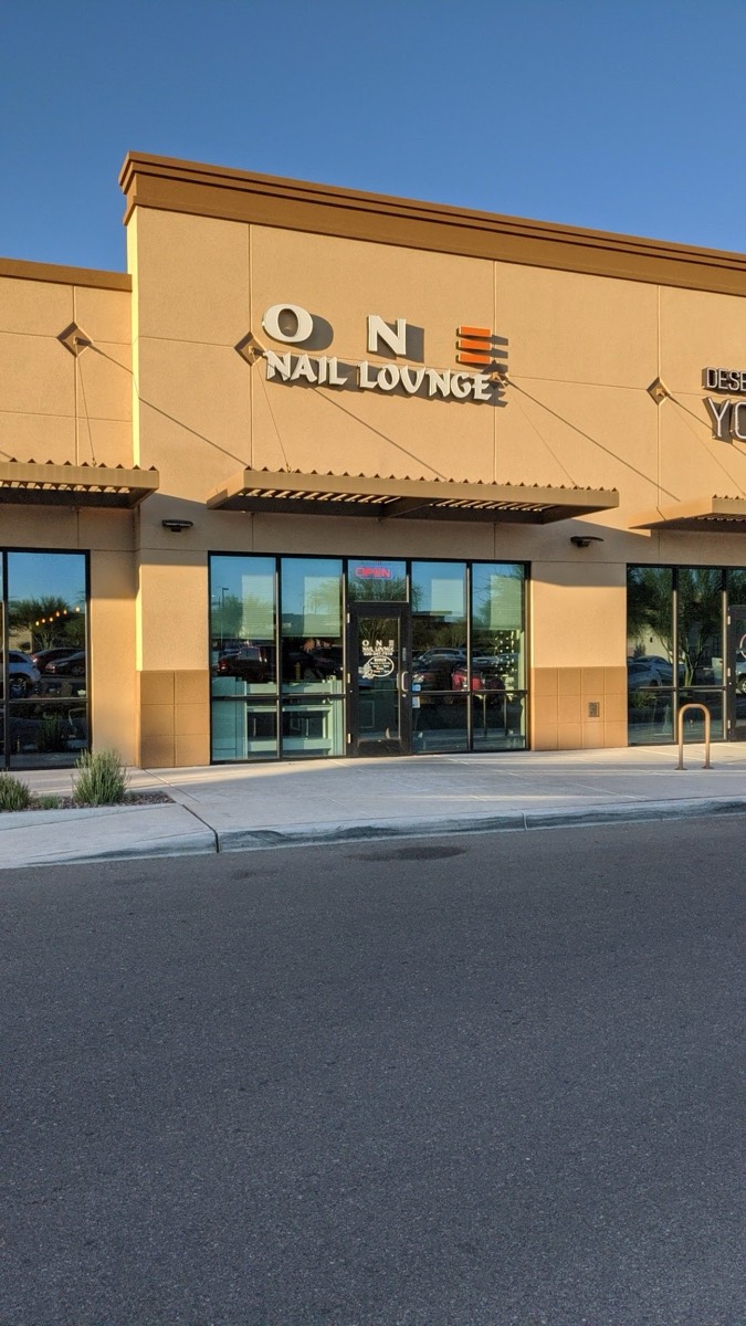 The tan storefront of ONE Nail Lounge with its sign above the glass entrance, in a Tucson plaza